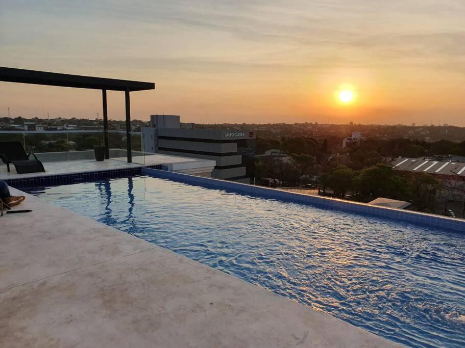 亚松森Hermoso departamento con piscina y estacionamiento的一座享有日落美景的建筑的顶部游泳池