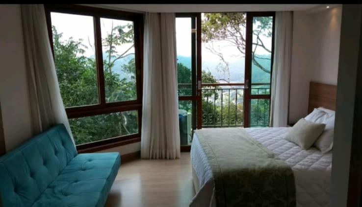 佩德拉阿祖尔Flat Vista Azul Hotel的一间卧室配有一张床、一张沙发和大窗户
