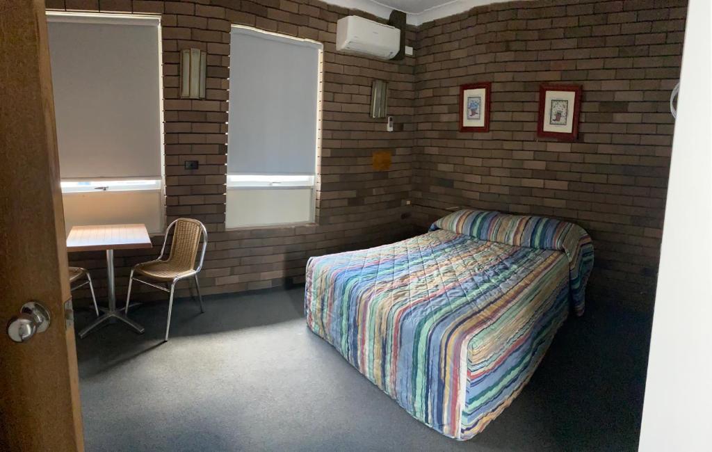 卧龙岗市区汽车旅馆的一间卧室配有一张床、一张桌子和一张书桌