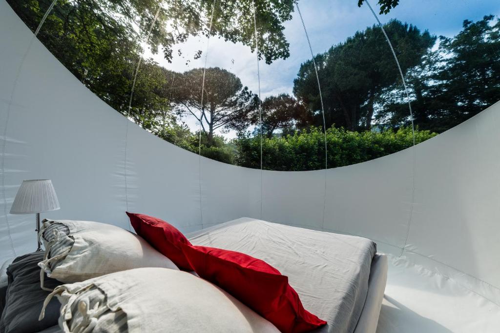 维科皮萨诺Bubble Room Under The Tuscan Stars Bubble的客房配有带红色枕头和镜子的床