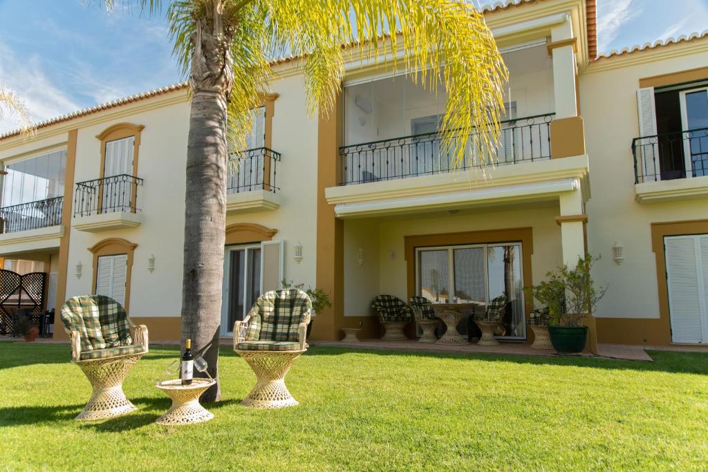 埃斯坦巴Carvoeiro, 2BR Pestana Gramacho Golf Apartment的院子里有棕榈树的大房子