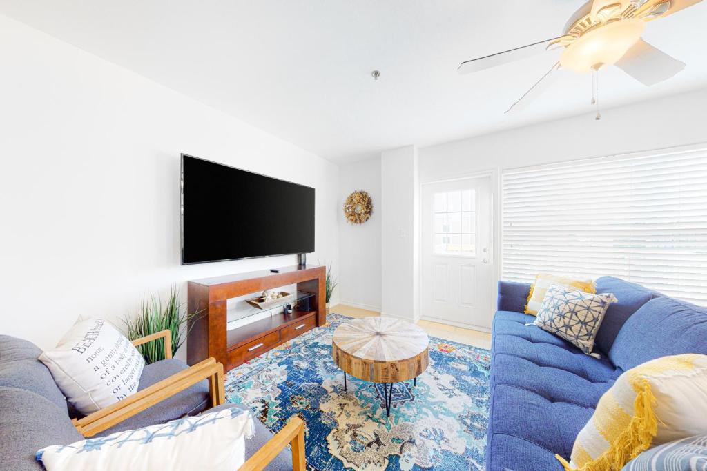南帕诸岛Star Beach Side Condominiums #105的客厅配有蓝色的沙发和电视