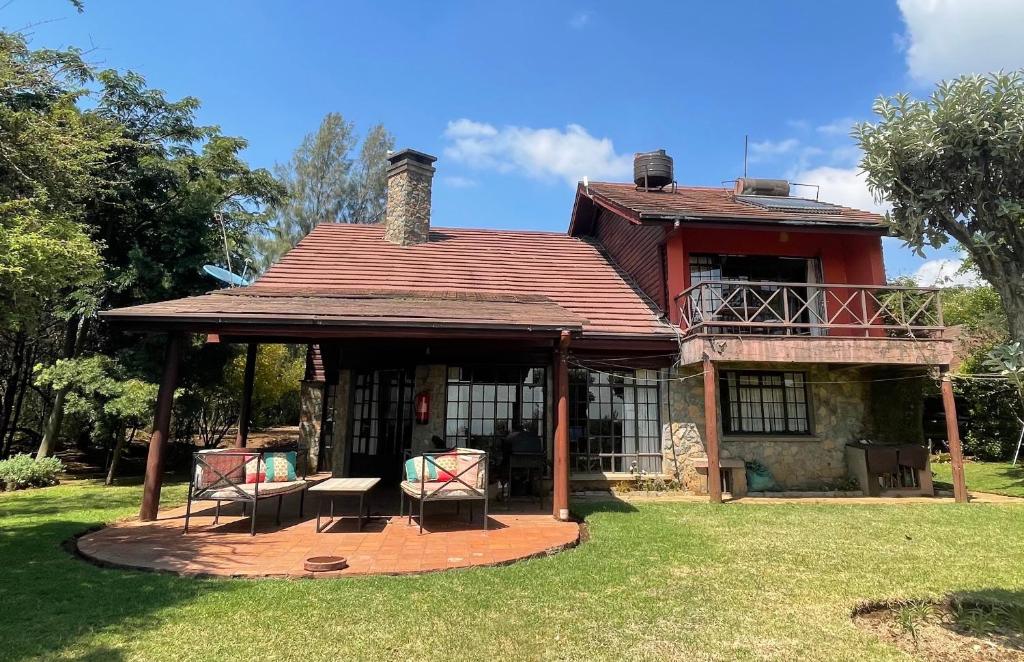 奈瓦沙Francolin Cottage at Great Rift Valley Lodge & Golf Resort Naivasha的一座带两把椅子和门廊的古老房子