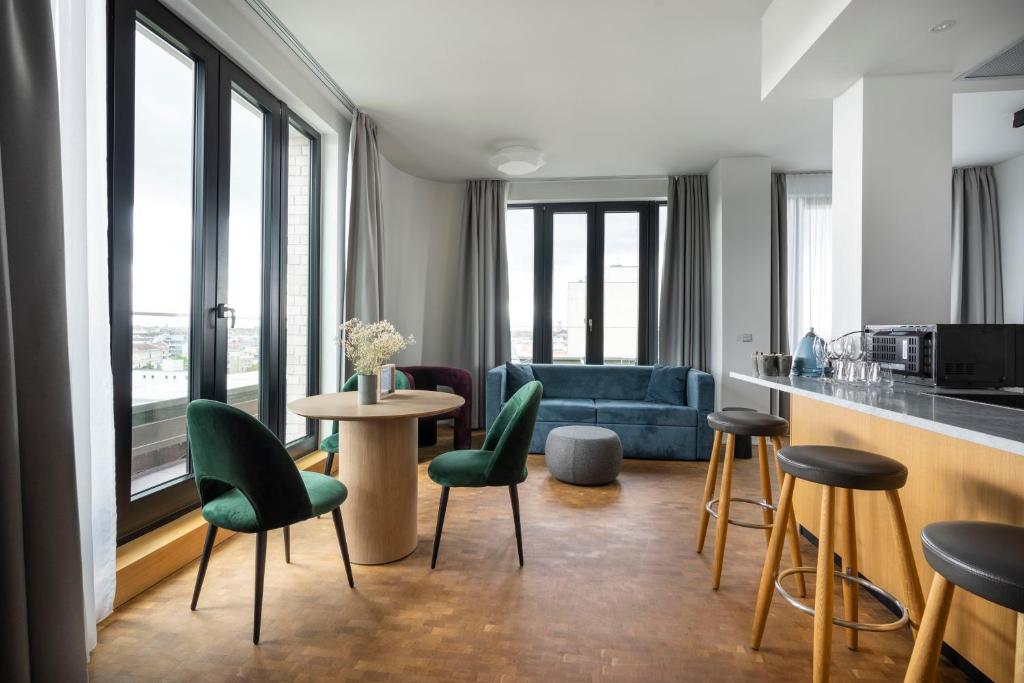 柏林numa l Drift Rooms & Apartments的厨房以及带绿色椅子和桌子的客厅。