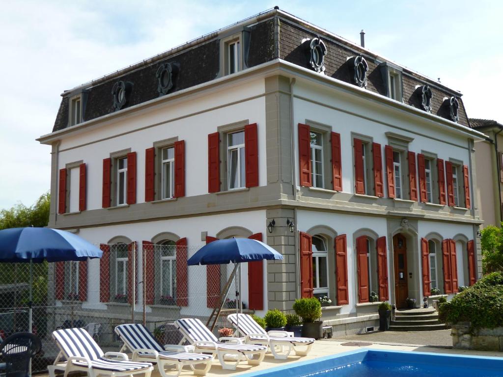 拉诺伊韦维尔加尔尼卡门别墅酒店的游泳池旁的一座带椅子和遮阳伞的建筑