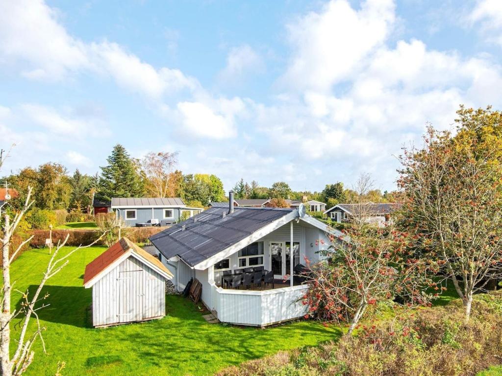 森讷比8 person holiday home in Juelsminde的一座白色的房子,在院子里设有太阳能屋顶