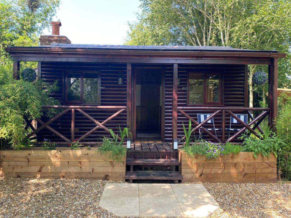 RibchesterLuxury Log Cabin with Outdoor Wood Fired Hot Tub & Pizza Oven的花园内的小木屋,设有门廊