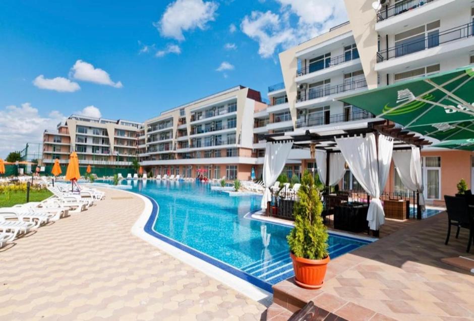阳光海滩Grand Kamelia Holiday Apartments的度假村的游泳池,配有椅子和遮阳伞