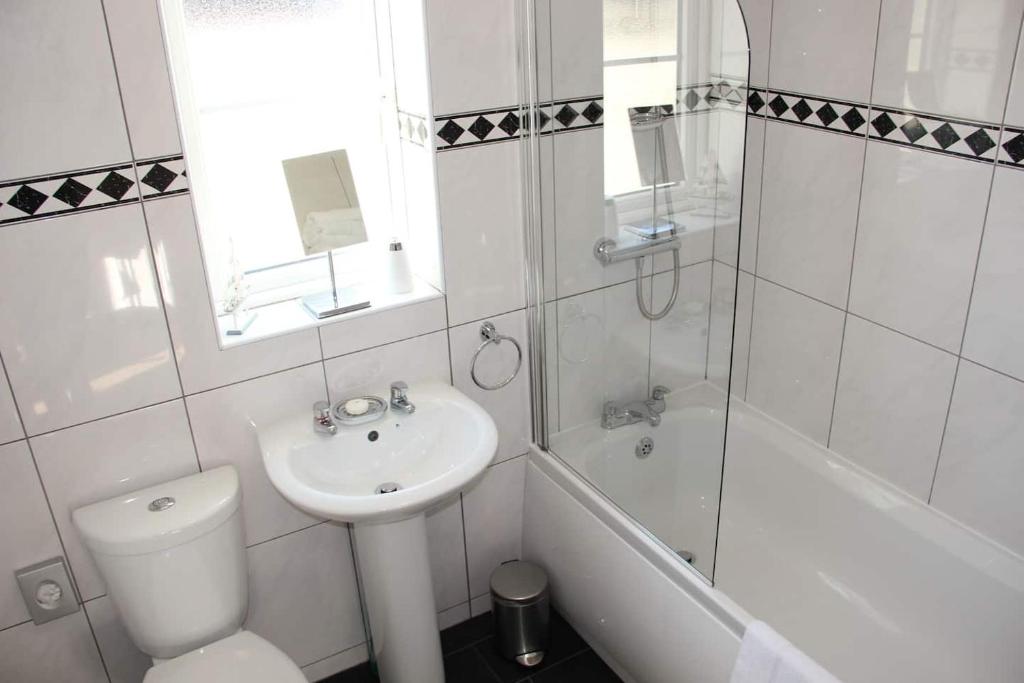 法尔茅斯5 Porth Gwel的白色的浴室设有水槽、卫生间和浴缸。