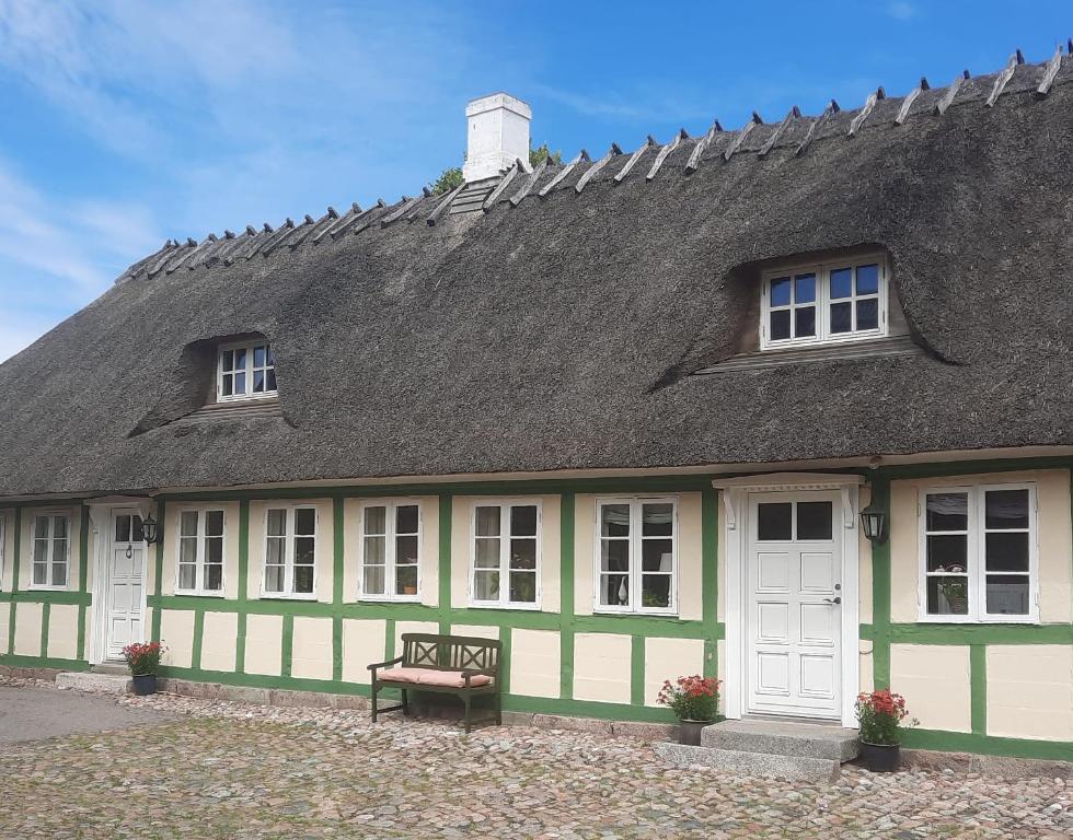 FlødstrupStaevnegaarden的绿色和白色的建筑,有屋顶和长凳