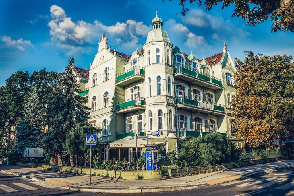 斯维诺乌伊希切Dom Zdrojowy Amber的一条树木繁茂的街道上白色的大建筑