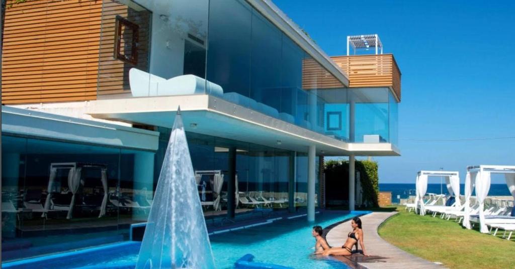 卡斯特拉巴特阿普罗多海水浴Spa度假酒店的两个女人坐在房子旁边的游泳池里