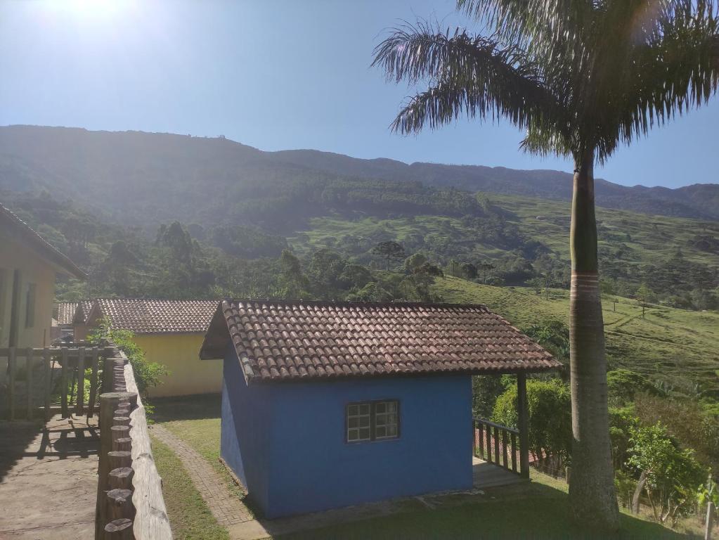 瓜拉廷格塔Pousada e restaurante Além das Nuvens的棕榈树和山的蓝色房子