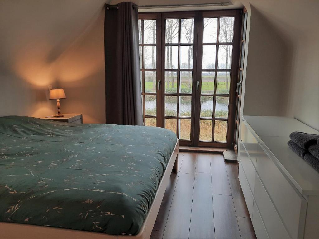 达默Cosy & charming holiday house in Damme的一间卧室设有一张床和一个大窗户