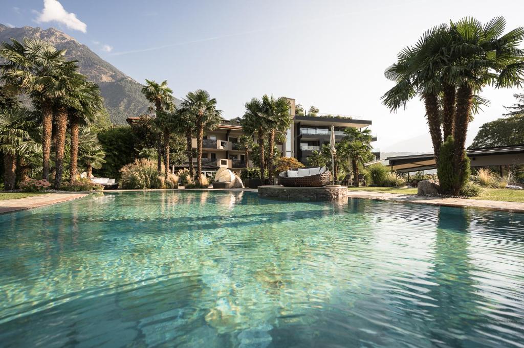 拉古多Hotel Das Dorner的一座棕榈树大型游泳池和一座建筑