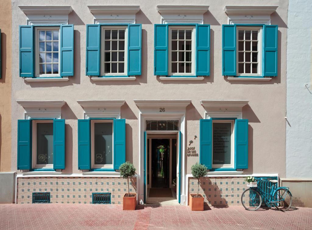马翁哈迪德赛斯布鲁克斯精品酒店的一座设有蓝色百叶窗的建筑,前面有一辆自行车停放