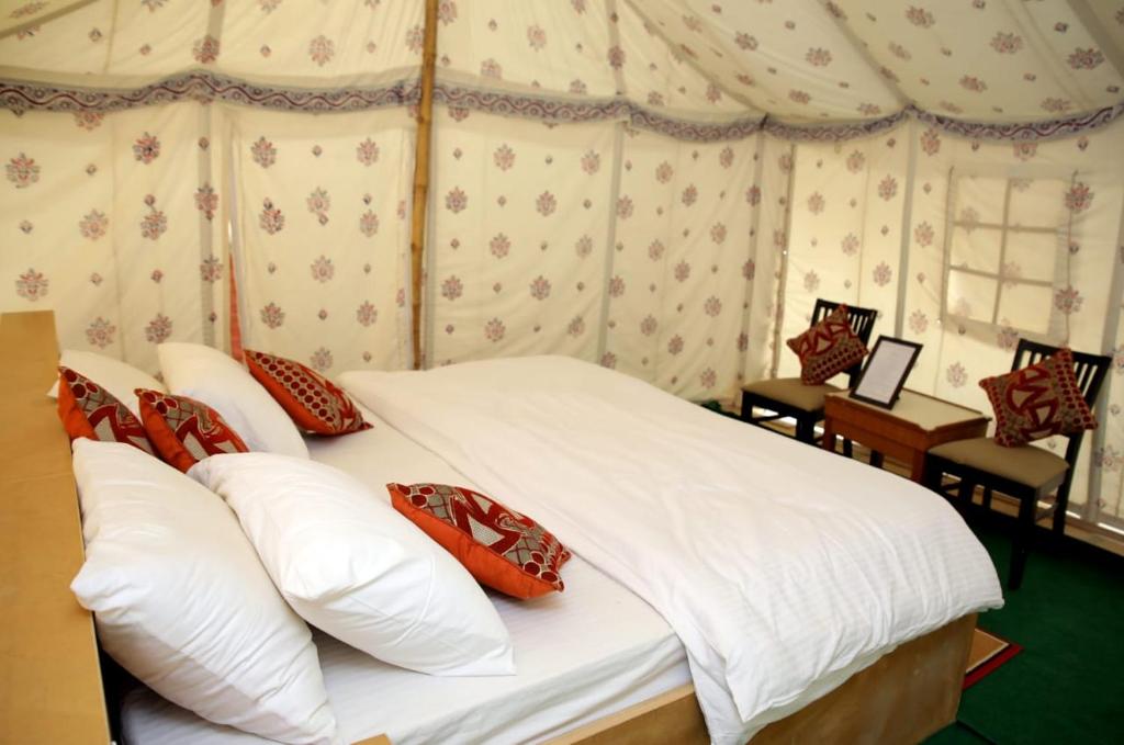 斋沙默尔Kingfisher Desert Camp的一间卧室配有带白色床单和红色枕头的床。