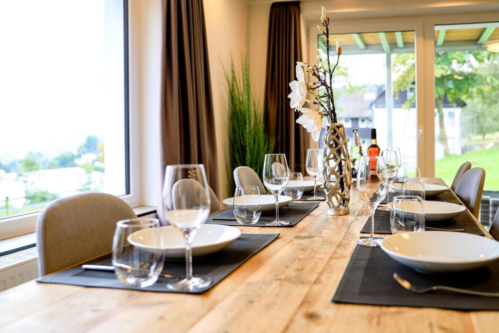 温特贝格Smart Resorts Haus Opal Ferienwohnung 401的长木桌子、椅子和酒杯
