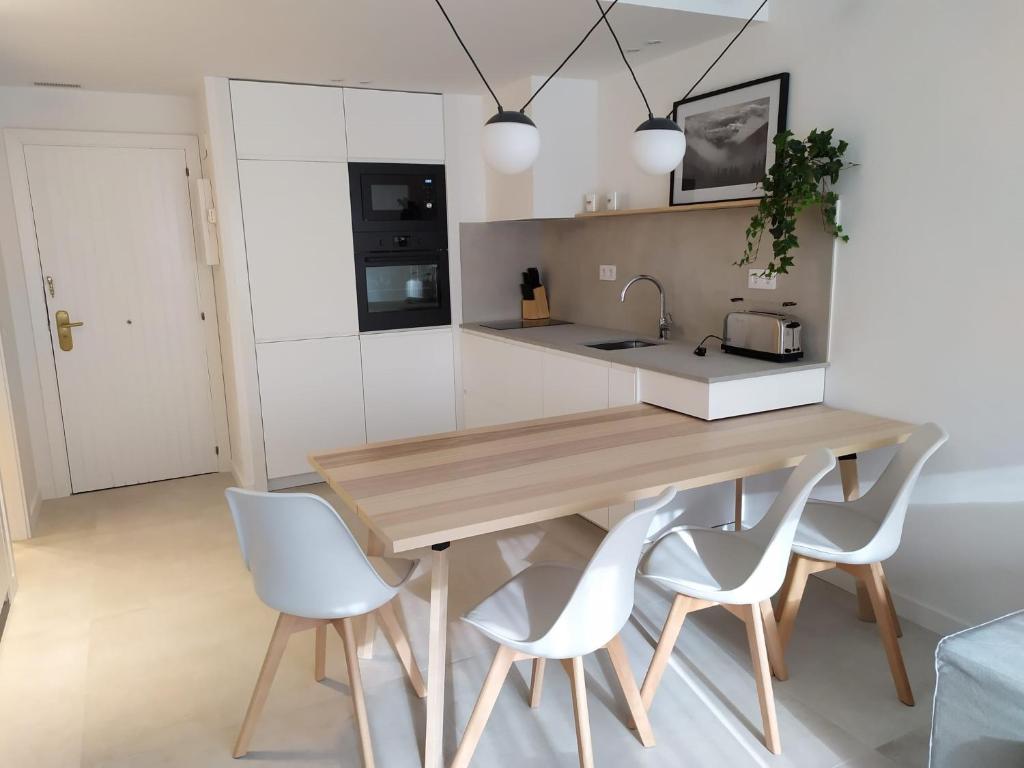 上阿兰Acogedor apartamento a pie de pistas cota 1500的厨房配有木桌和白色椅子