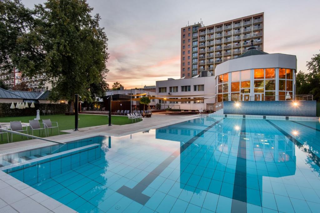 豪伊杜索博斯洛Hotel Barátság的酒店游泳池的背景是一座建筑