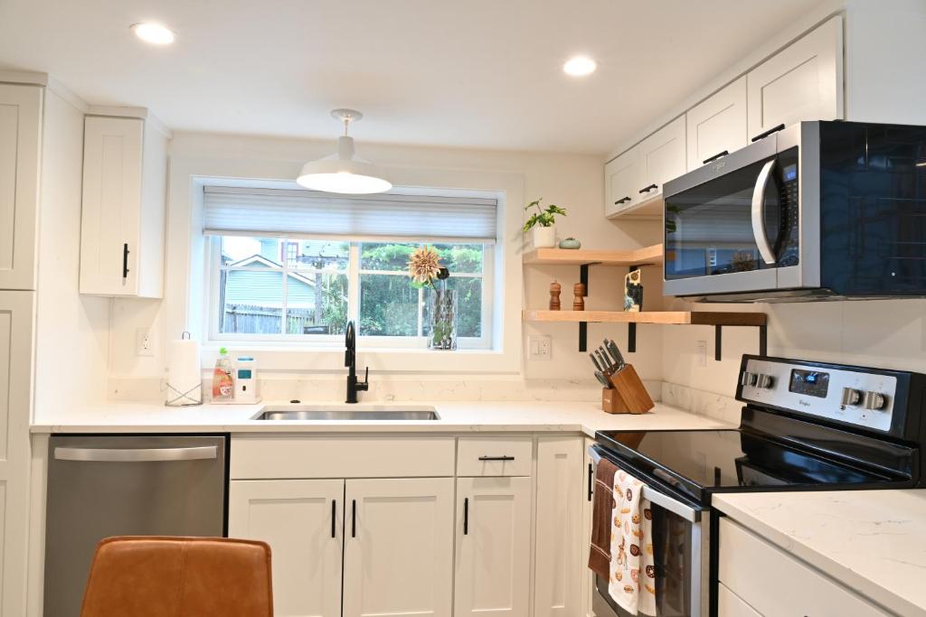 西雅图Modern and warm house的厨房配有白色橱柜、水槽和窗户。
