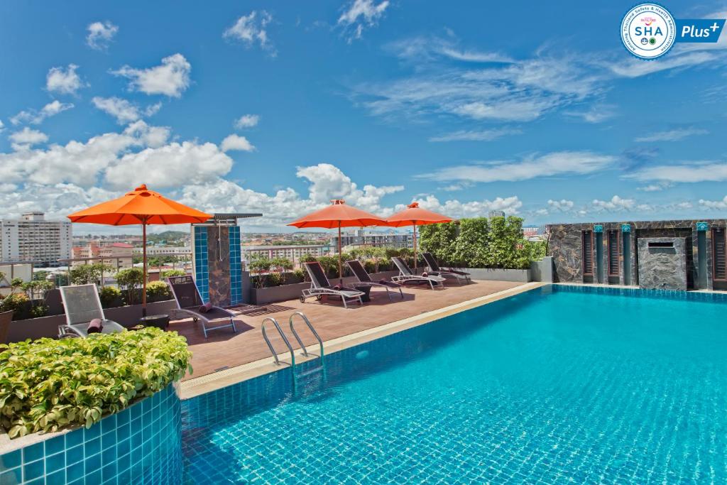芭堤雅市中心Adelphi Pattaya - SHA Extra Plus的一座带遮阳伞的建筑屋顶上的游泳池