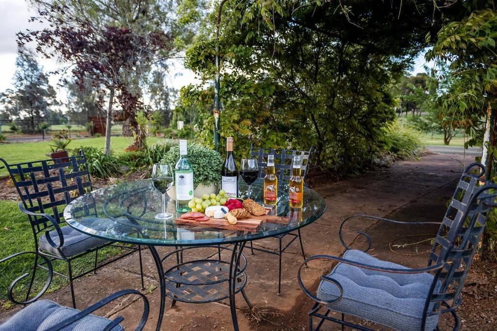 帕克斯EdenValley Private Manicured Gardens with Fire Pit的玻璃桌,上面装有葡萄酒和食物
