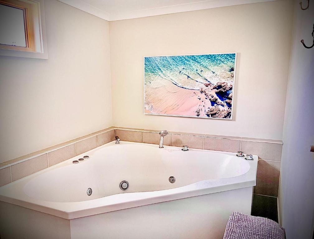 斯旺西Churchill's B&B twin spa getaway Studio的带浴缸的浴室,墙上有绘画作品
