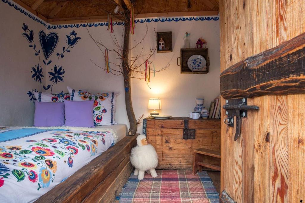 波切尼斯Folklórna chyža的一间卧室配有一张床铺,旁边是一只白色的狗