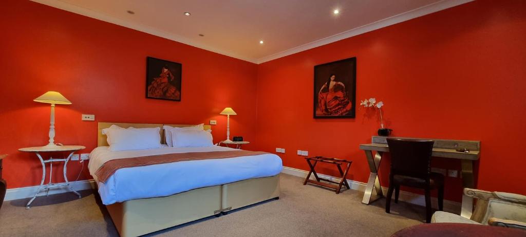 桑希尔巴克卢和昆斯伯里阿姆斯力推酒店的一间卧室设有红色的墙壁、一张床和一张书桌