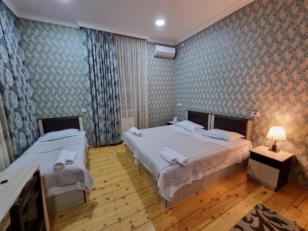 阿哈尔齐赫HOTEL JULIA Akhaltsikhe的一间卧室配有两张床和一张带台灯的桌子