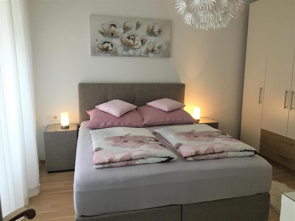 林茨Ferienwohnung DANUBIA的一间卧室配有一张带粉红色枕头和吊灯的床。