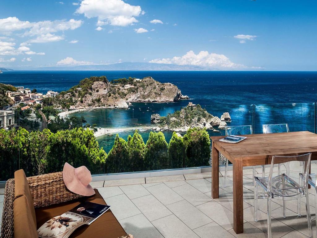 陶尔米纳贝拉岛公寓的阳台配有桌子,享有海景。