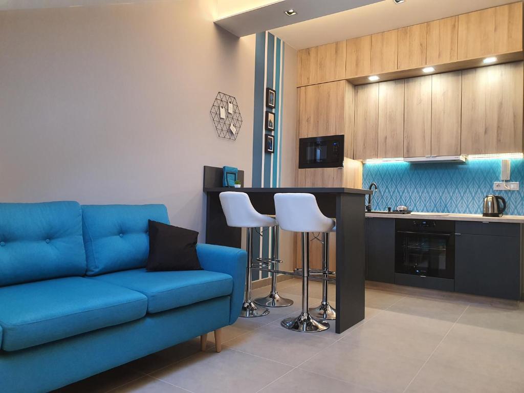考波什堡Kaposvár Apartman的一间带蓝色沙发的客厅和一间厨房