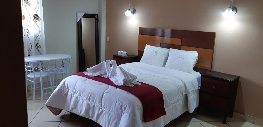 卡哈马卡Hotel Alpamayo Cajamarca的一间卧室配有一张带白色床单和椅子的床