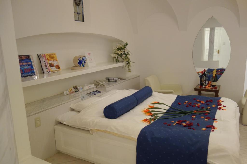 池田第一情趣酒店（仅限成人）的一间卧室配有一张白色的床和蓝色的毯子