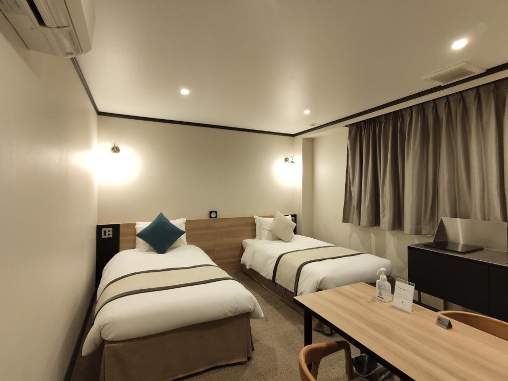 东京yksi SAUNA & STAY的酒店客房设有两张床和一张桌子。