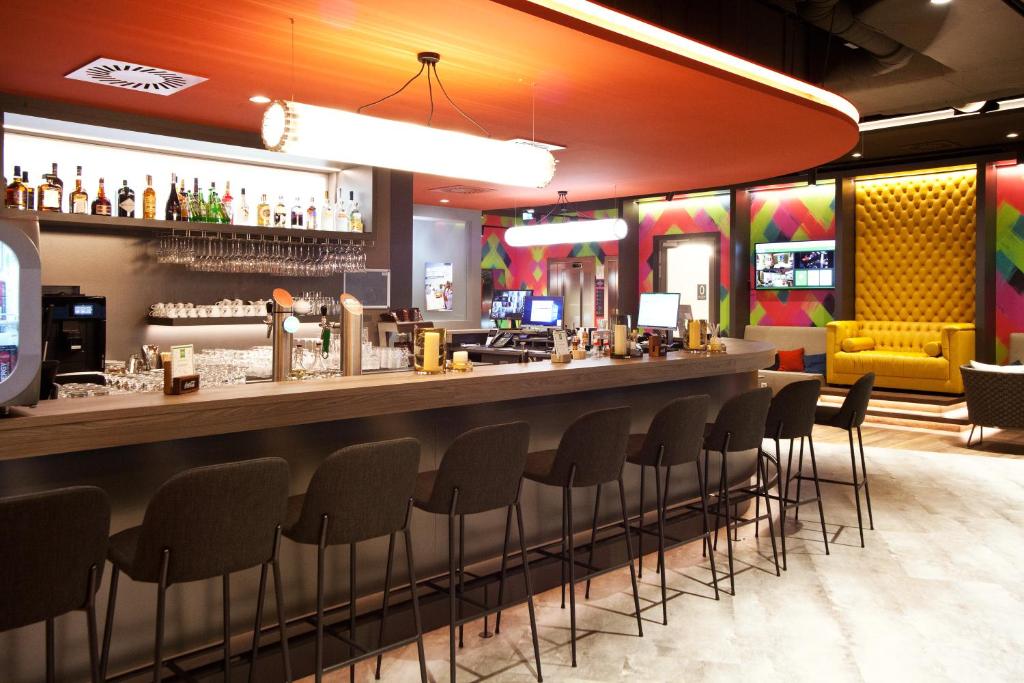 帕恩多夫ibis Styles Parndorf Neusiedler See的餐厅里的酒吧,周围摆放着椅子