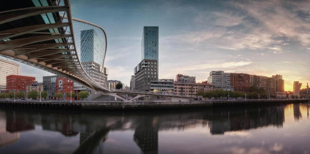 毕尔巴鄂Bilbao City Center by abba Suites的一座建有建筑物的城市里河流上的桥梁
