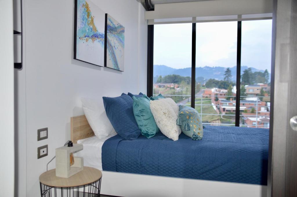 危地马拉Cozy Stays Cayala Apartments 7的一间卧室配有一张带蓝色床单的床和一扇窗户。
