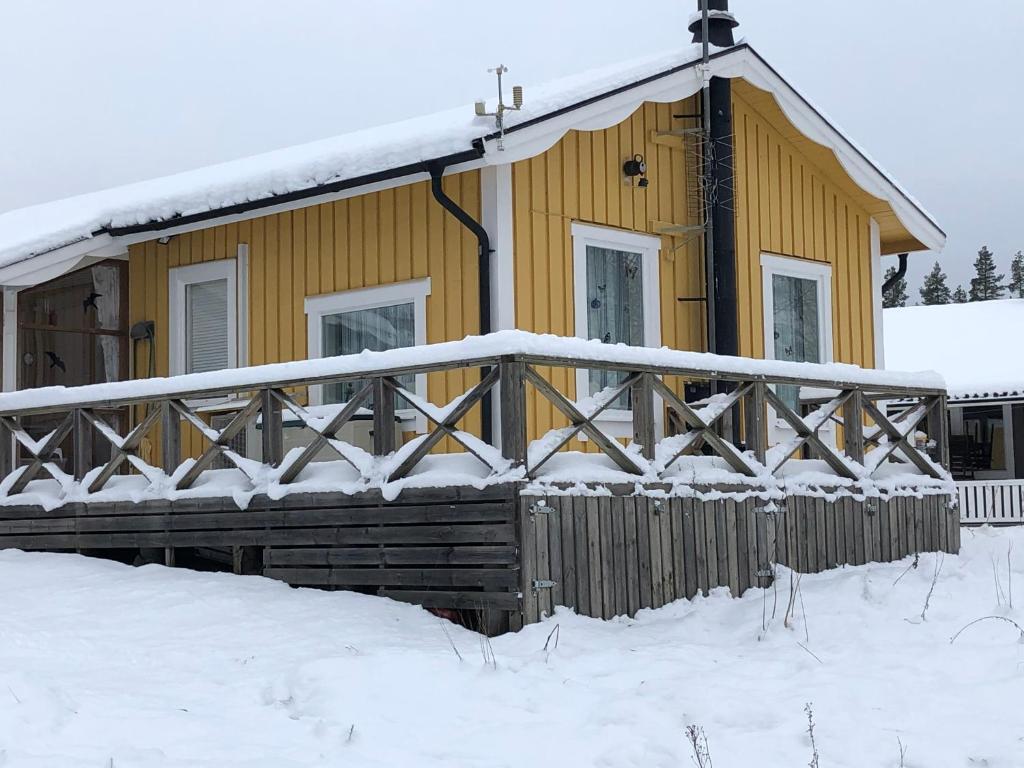 拉达Vakantiewoning aan het water的雪中带木栅栏的黄色房子