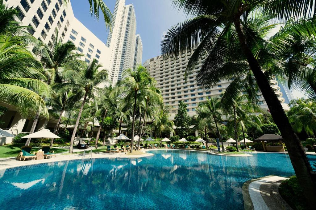 马尼拉Edsa Shangri-La, Manila的一座棕榈树和建筑的大型游泳池