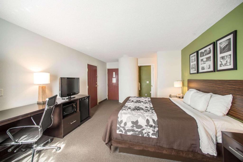 LarkdaleSleep Inn Decatur I-72的酒店客房设有一张床、一张书桌和一台电视机。