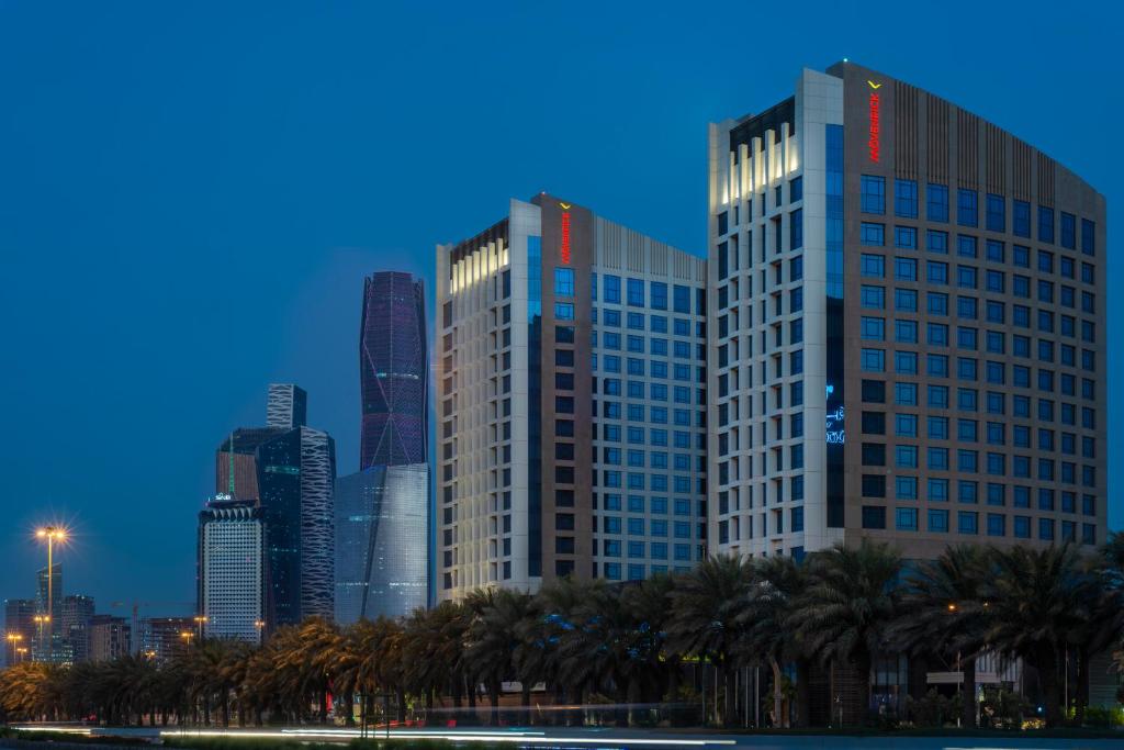 利雅德Movenpick Hotel and Residences Riyadh的棕榈树和建筑的城市天际线
