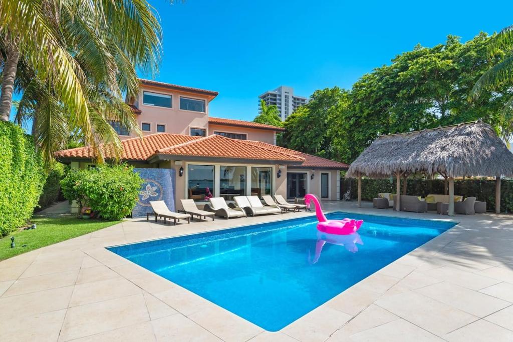 迈阿密Villa Toscana - Luxury with Pool的一个带粉红色椅子和房子的游泳池