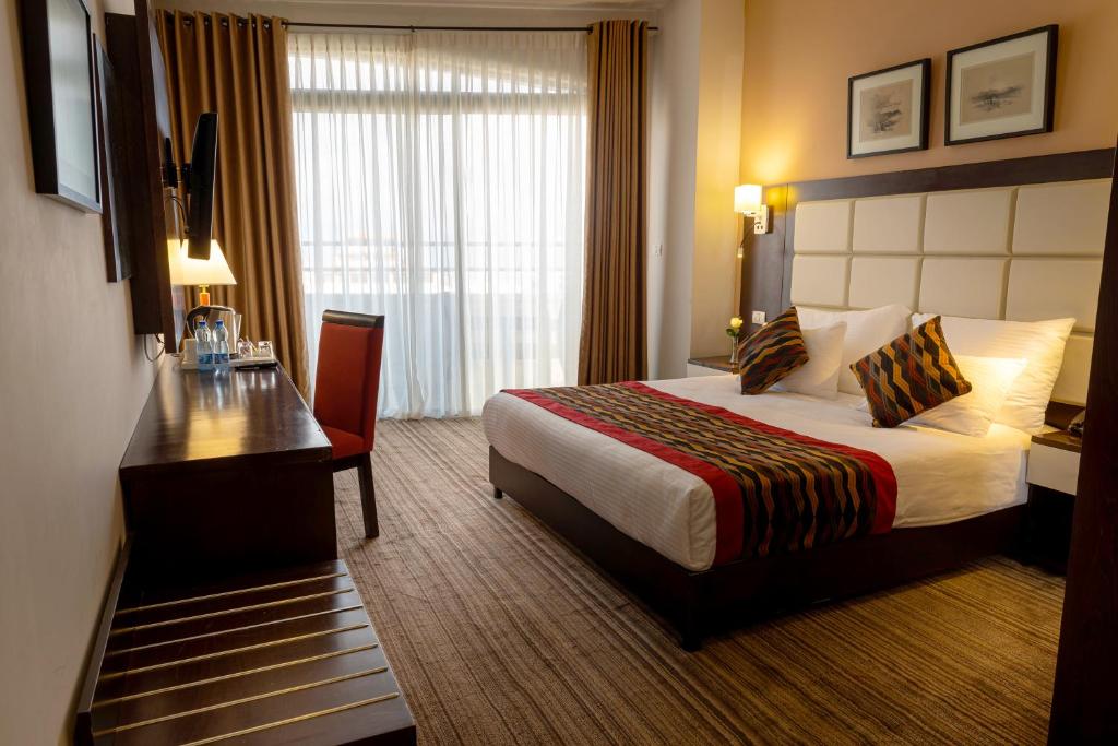 伯利恒Ambassador City Hotel - Bethlehem的酒店客房配有一张床铺、一张桌子和一张书桌。