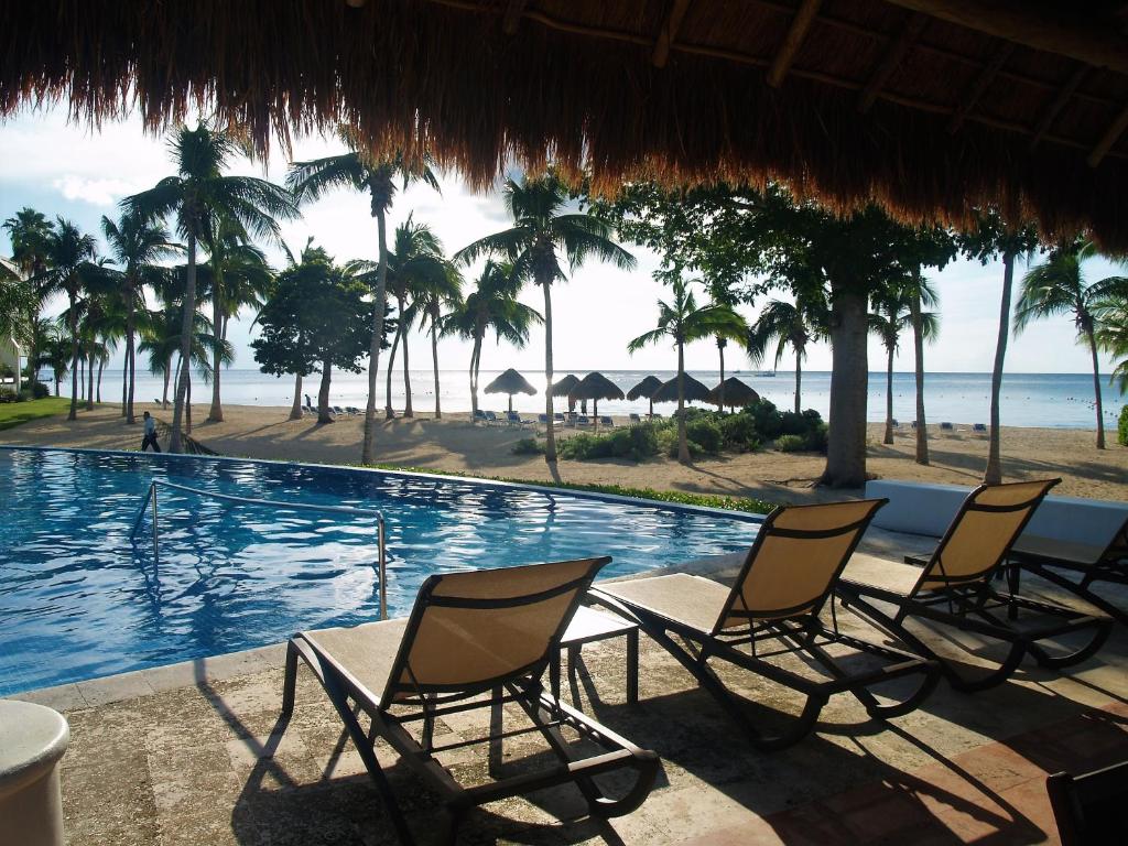 科苏梅尔Beachfront Apartment Your Home in Cozumel的一组椅子坐在游泳池旁