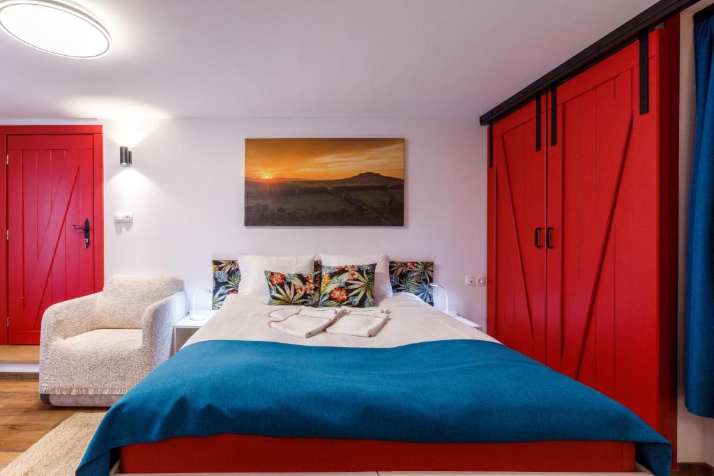 赫维兹Origo Vendégház的一间卧室配有红色橱柜、一张床和一把椅子