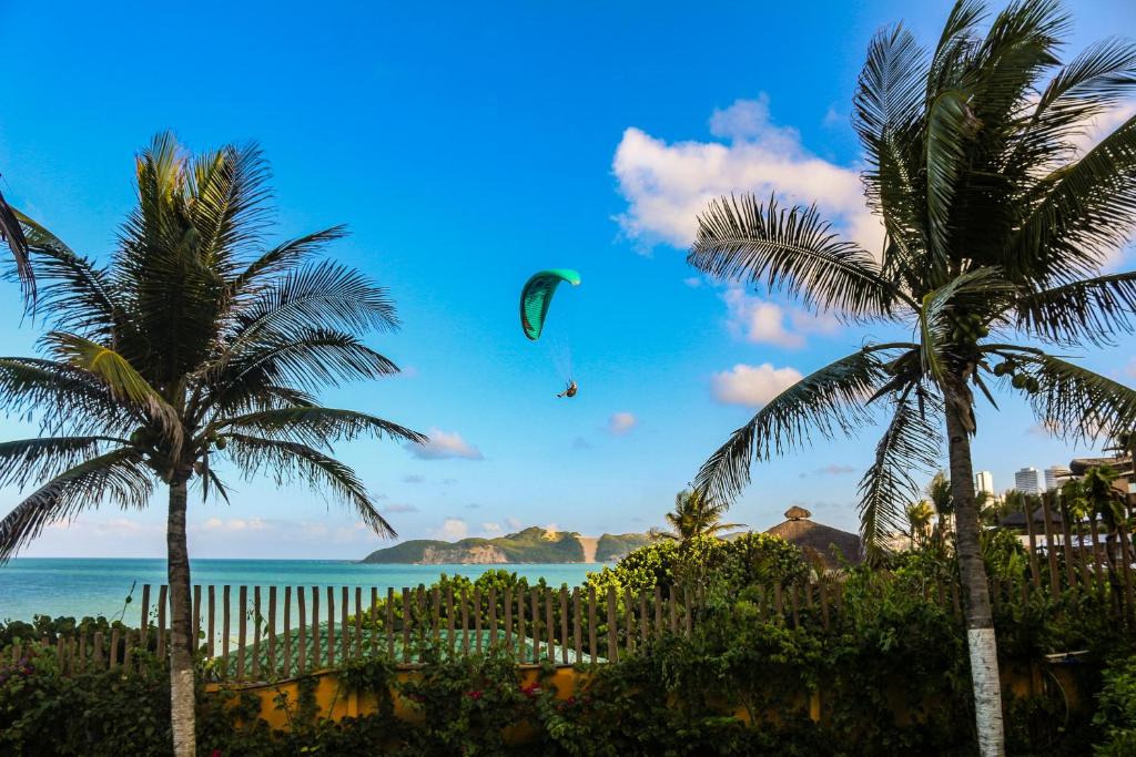 纳塔尔Atlântico Flat Natal的一只手风筝在海面上,棕榈树飞翔的人