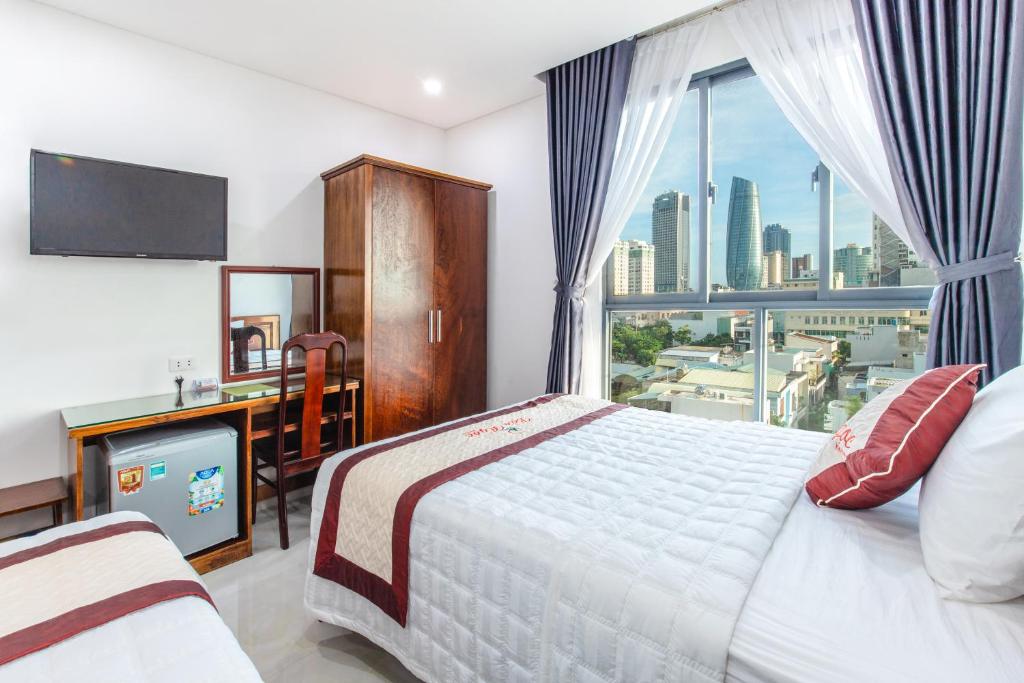 岘港Bao Ngoc Hotel & Apt的一间卧室配有一张床、一张书桌和一个窗户。